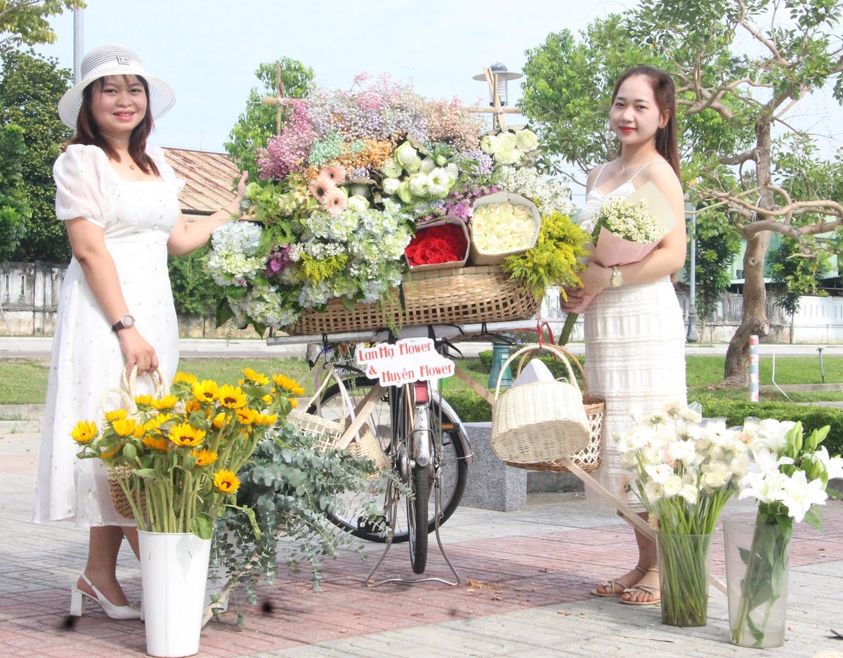 Bạn trẻ chụp ảnh bên xe hoa tươi.