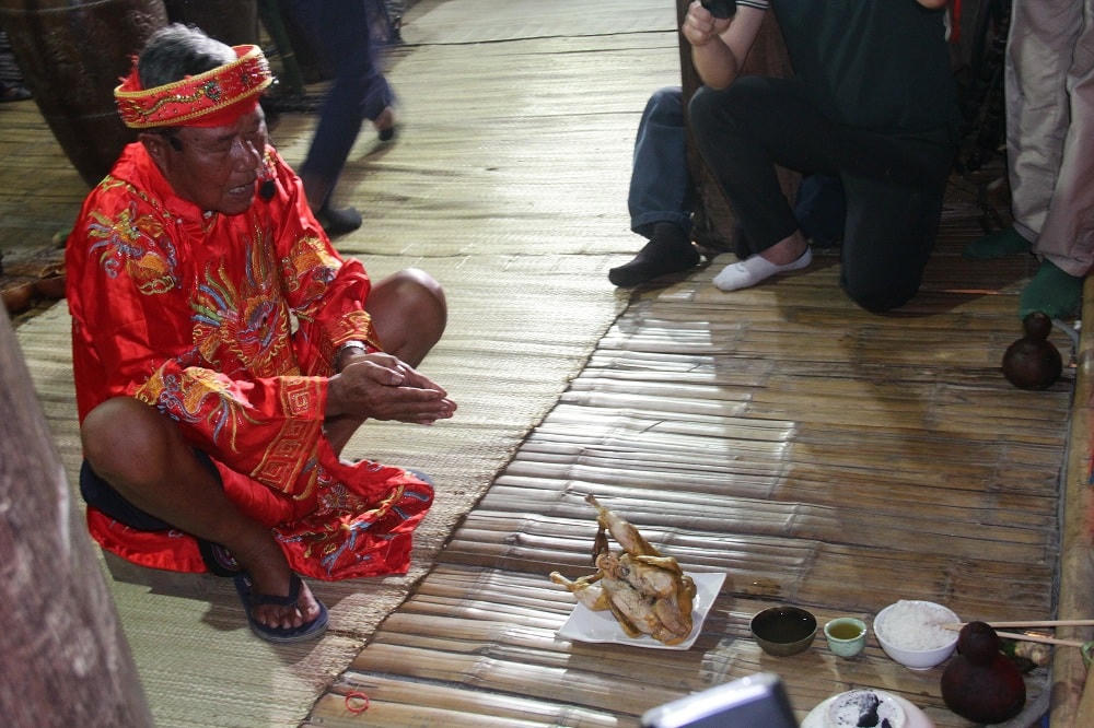 Thầy cúng cầm con gà lên miệng ché rồi khấn: Vì con gà là biểu trưng lời kêu gọi, lời mời các thần linh, tổ tiên ông bà, mọi người trong buôn chuẩn bị trang phục đẹp, ché ngon tham dự lễ hội…