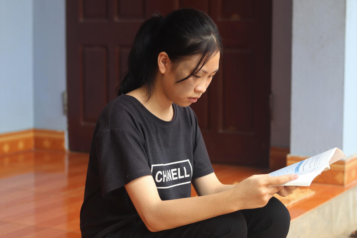Tranh thủ lúc trời sáng, Mai mang sách ra ngoài hiên để học.
