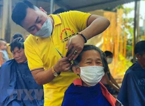 Anh Ngô Trọng Giáp cắt tỉa, căn chỉnh cẩn thận từng mái tóc cho bệnh nhân đang điều trị tại Bệnh viện Đa khoa huyện Triệu Phong. Ảnh: TTXVN. 