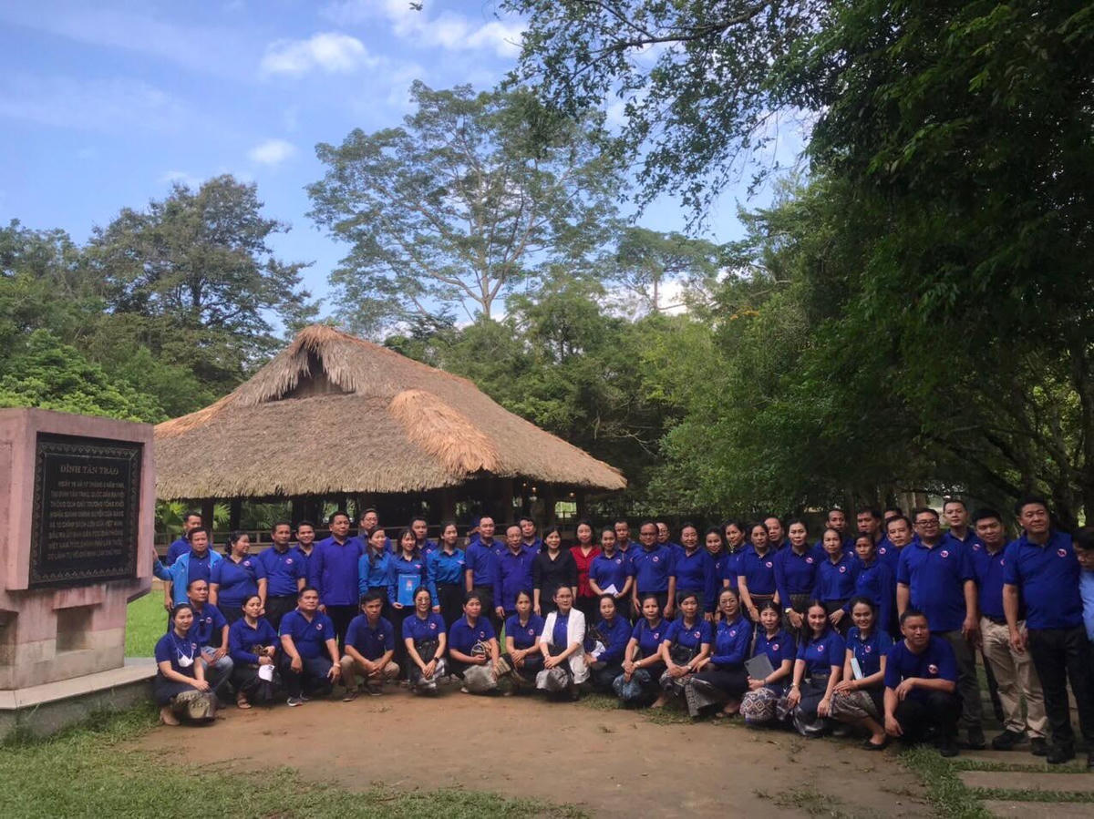 Đoàn đại biểu Trung ương Đoàn Thanh niên Lào chụp ảnh lưu niệm tại Lán Là Nưa nơi Bác Hồ ở và làm việc.
