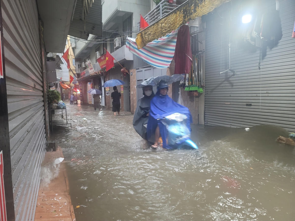 Nhiều ngõ ngập lụt, đường phố tắc đường, người dân vất vả lưu thông trên đường.
