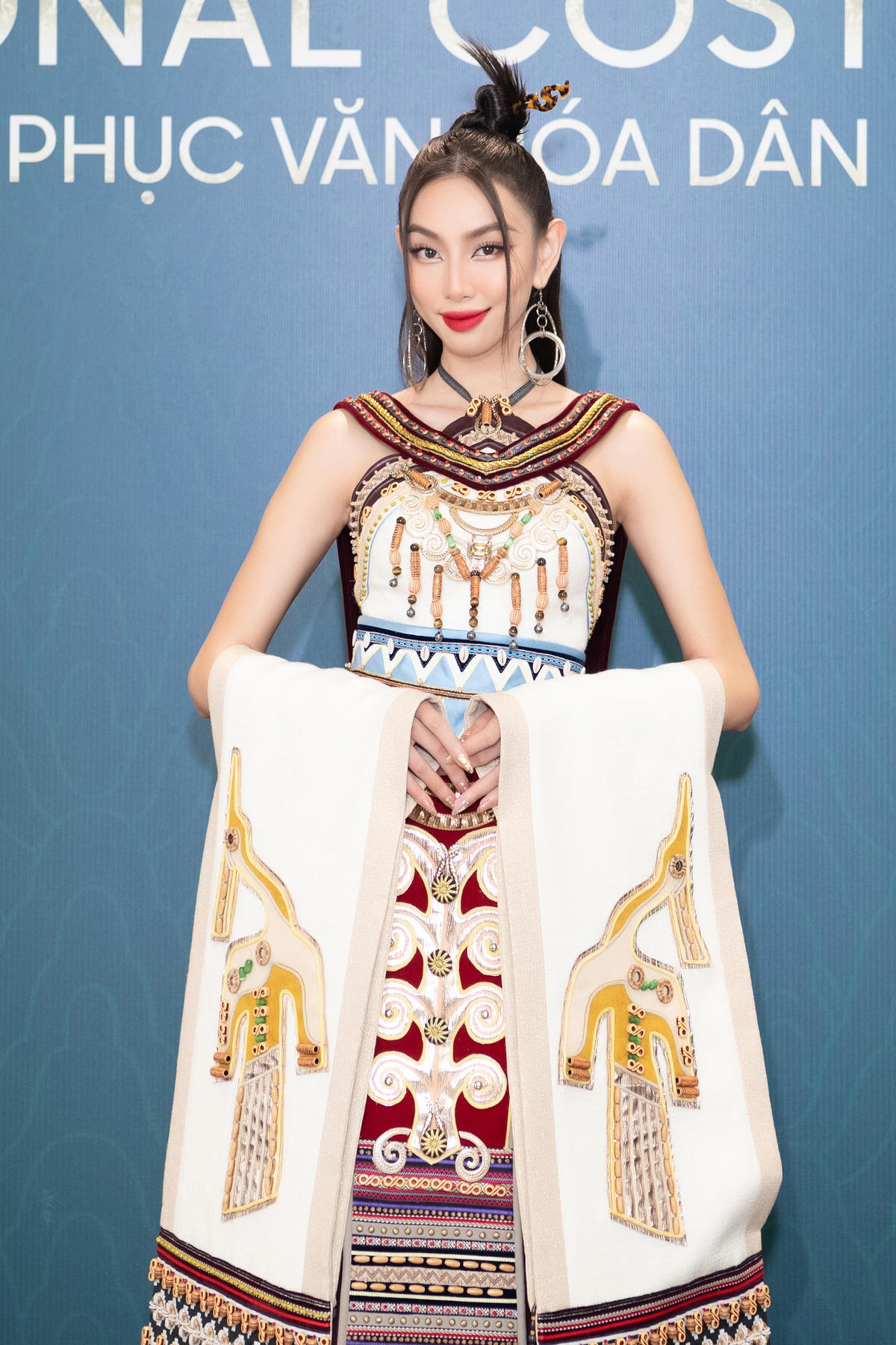 Xuất hiện tại đêm thi, Miss Grand International 2021 Nguyễn Thúc Thùy Tiên diện trên mình bộ trang phục vô cùng hoành tráng với những chi tiết hoa văn thổ cẩm, chim hạc đậm chất dân tộc Việt kết hợp cùng phụ kiện hoa tai tròn mang điểm nhấn hiện đại. 
