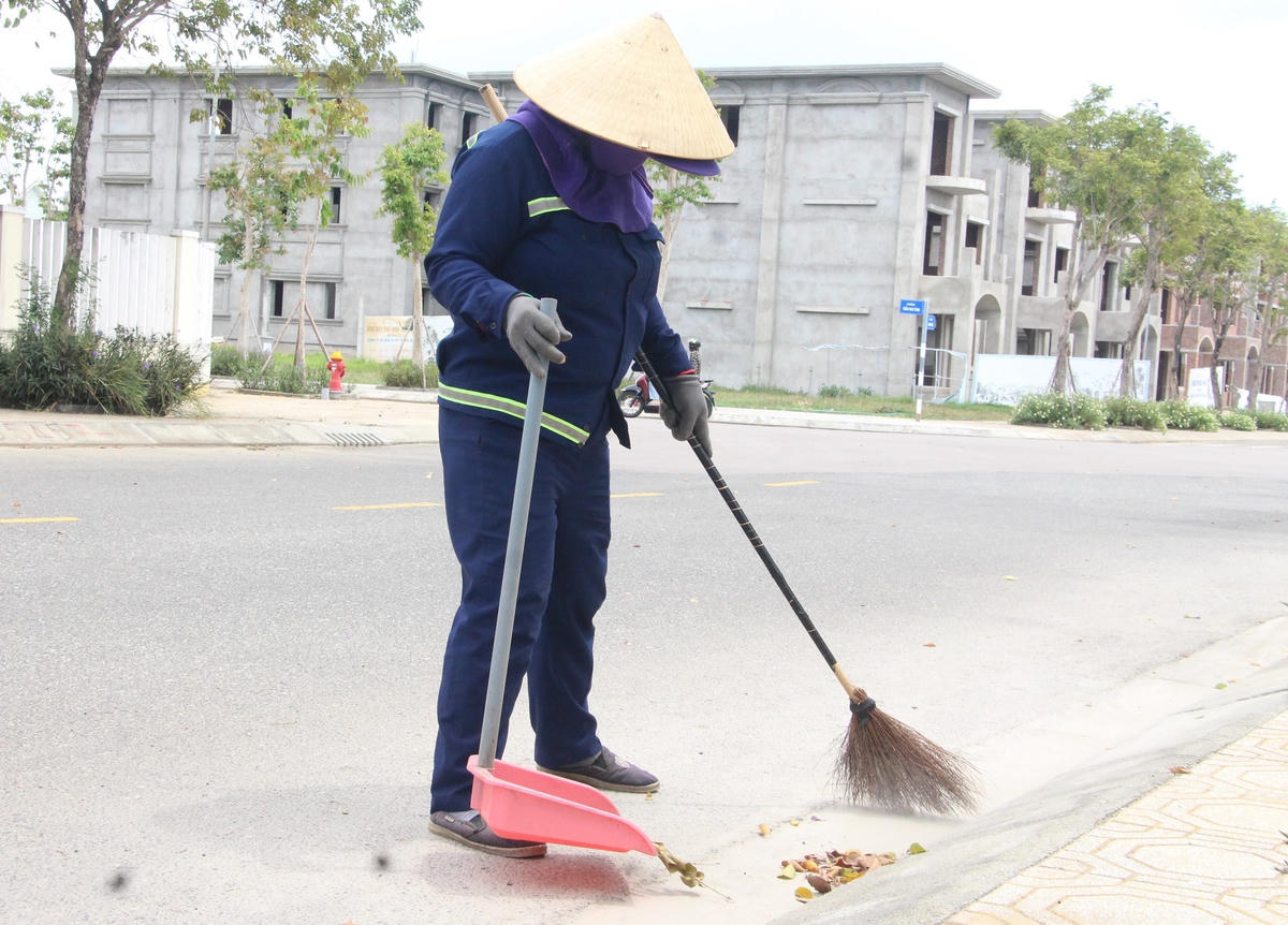 Công nhân đứng giữa trời nắng để quét dọn rác.