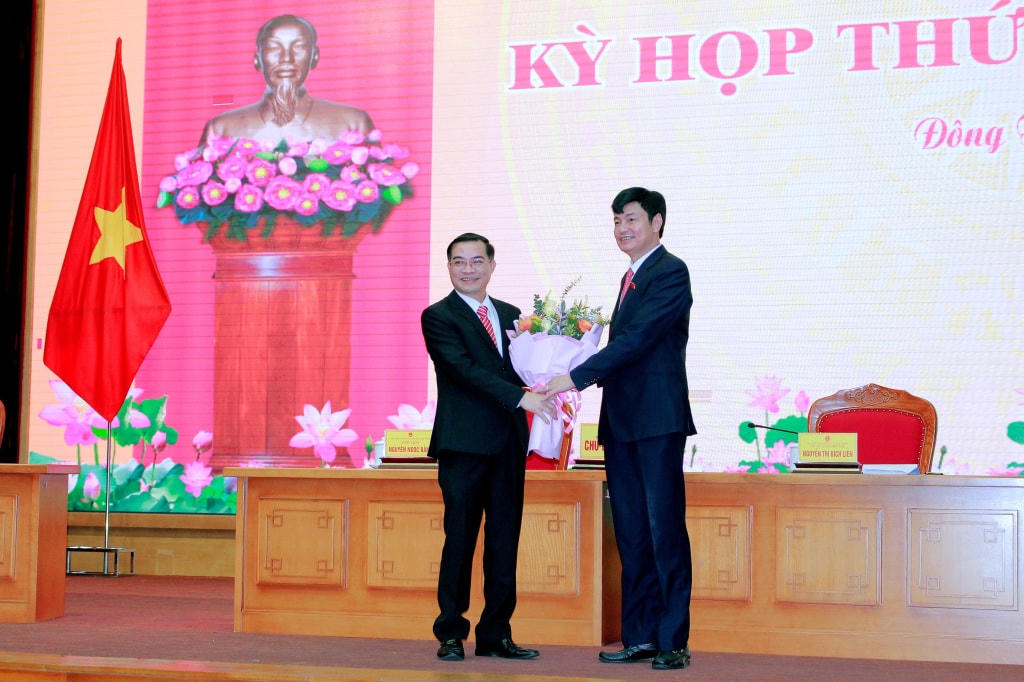 Chủ tịch HĐND thị xã Đông Triều tặng hoa chúc mừng ông Lê Văn Độ, Phó Chủ tịch UBND thị xã (bên trái). Ảnh: QMG.