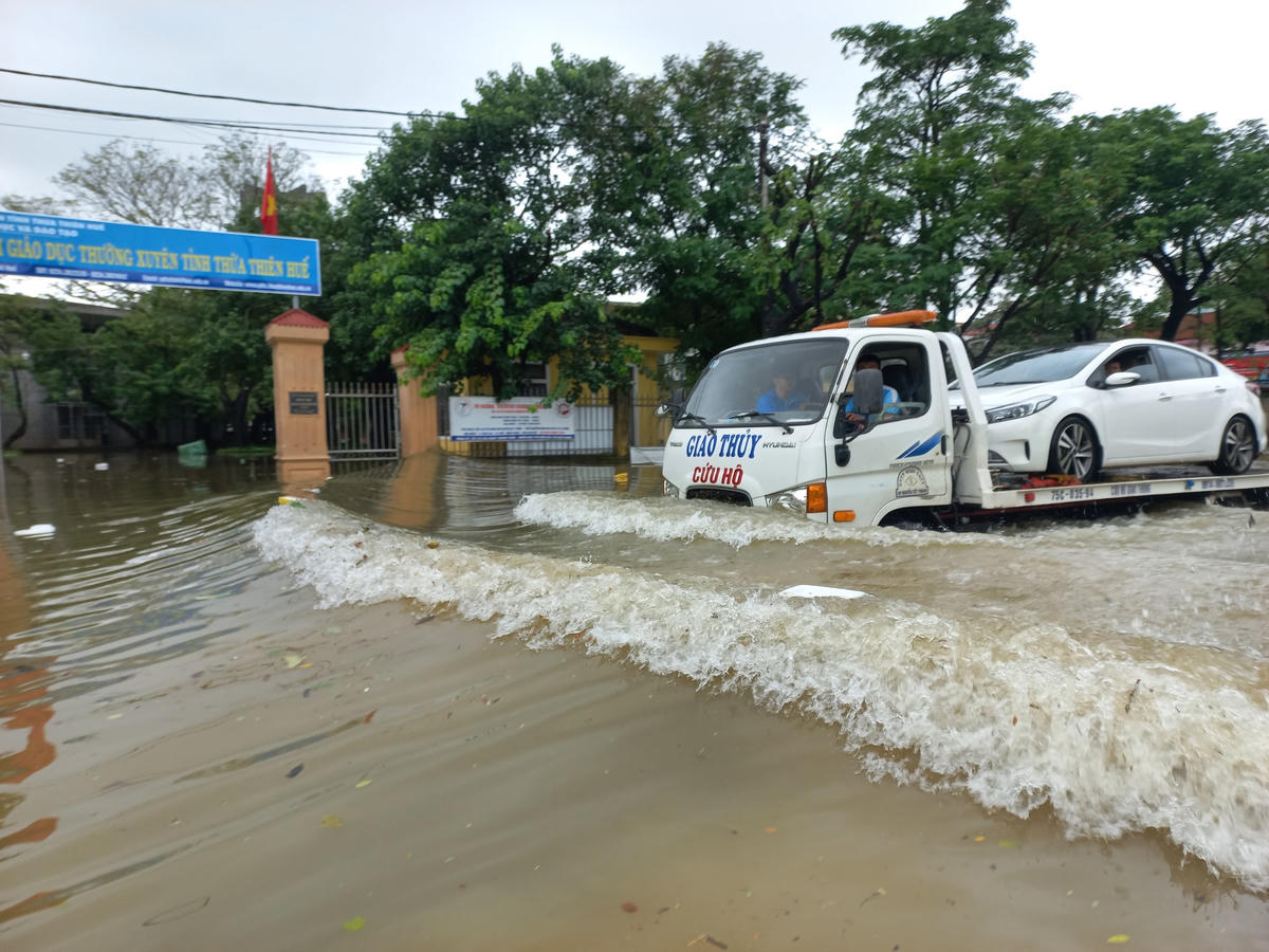 Nhiều xe ô tô phải dùng xe cứu hộ để di chuyển qua đoạn đường bị ngập sâu.
