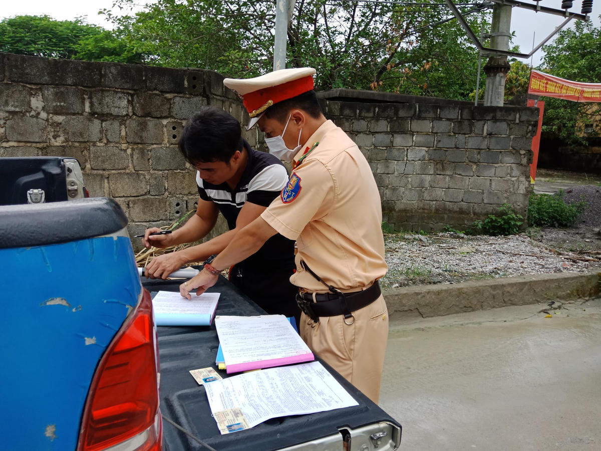 Tài xế ký vào biên bản xử phạt vì lỗi để rơi vãi đất đá ra đường gây mất an toàn giao thông.