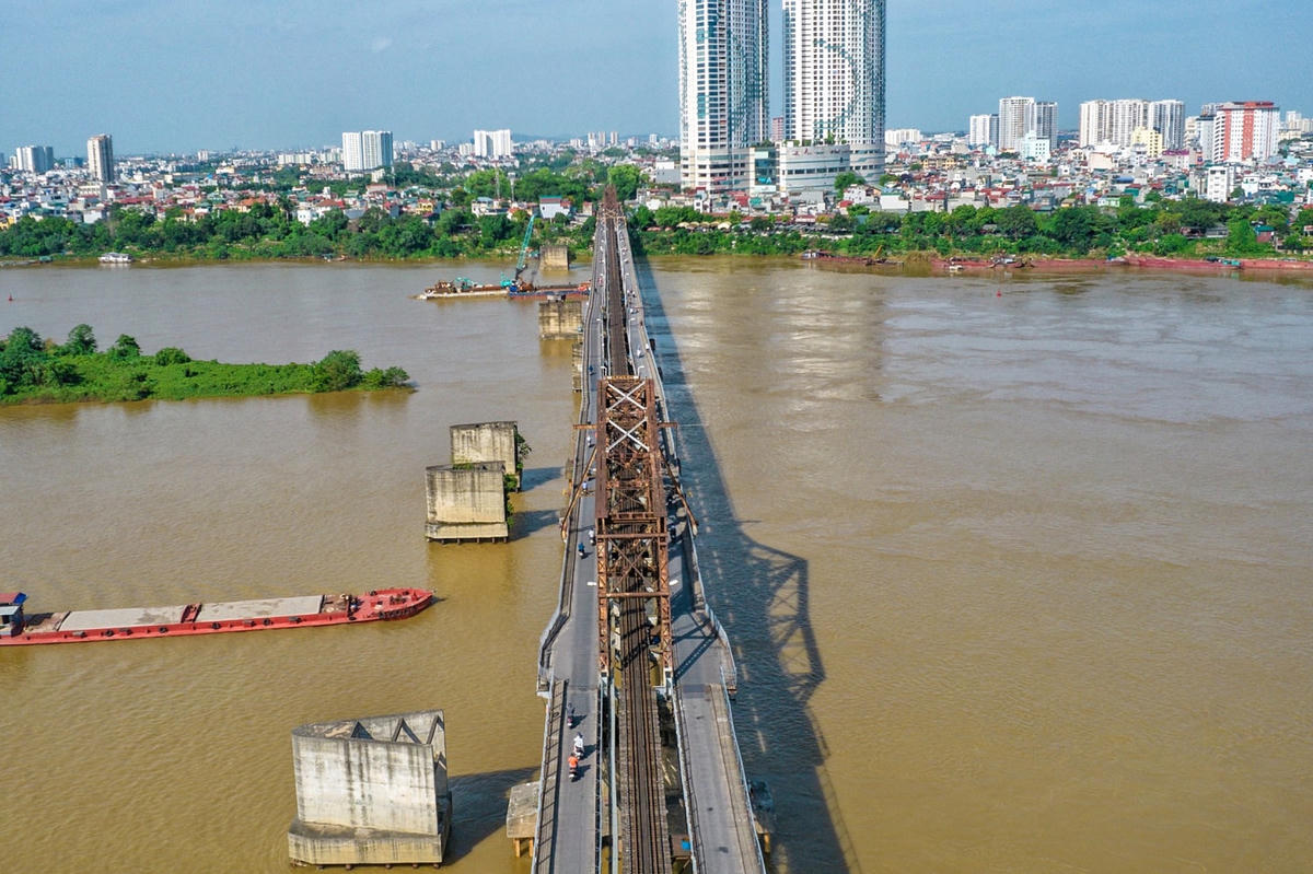 Làm việc trong môi trường nắng nóng 38-39 độ C, những thanh thép trên cầu càng thêm nóng rãy, hơi nóng phả ra nhưng các công nhân ở đây vẫn miệt mài đeo, bám các thanh thép, sơn sửa lại cầu.