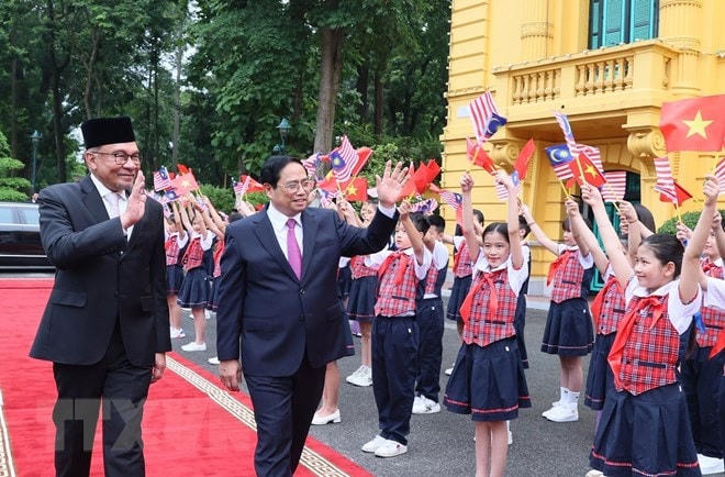 Thủ tướng Phạm Minh Chính và Thủ tướng Malaysia Anwar Ibrahim với thiếu nhi Thủ đô tại lễ đón. (Ảnh: Dương Giang/TTXVN).