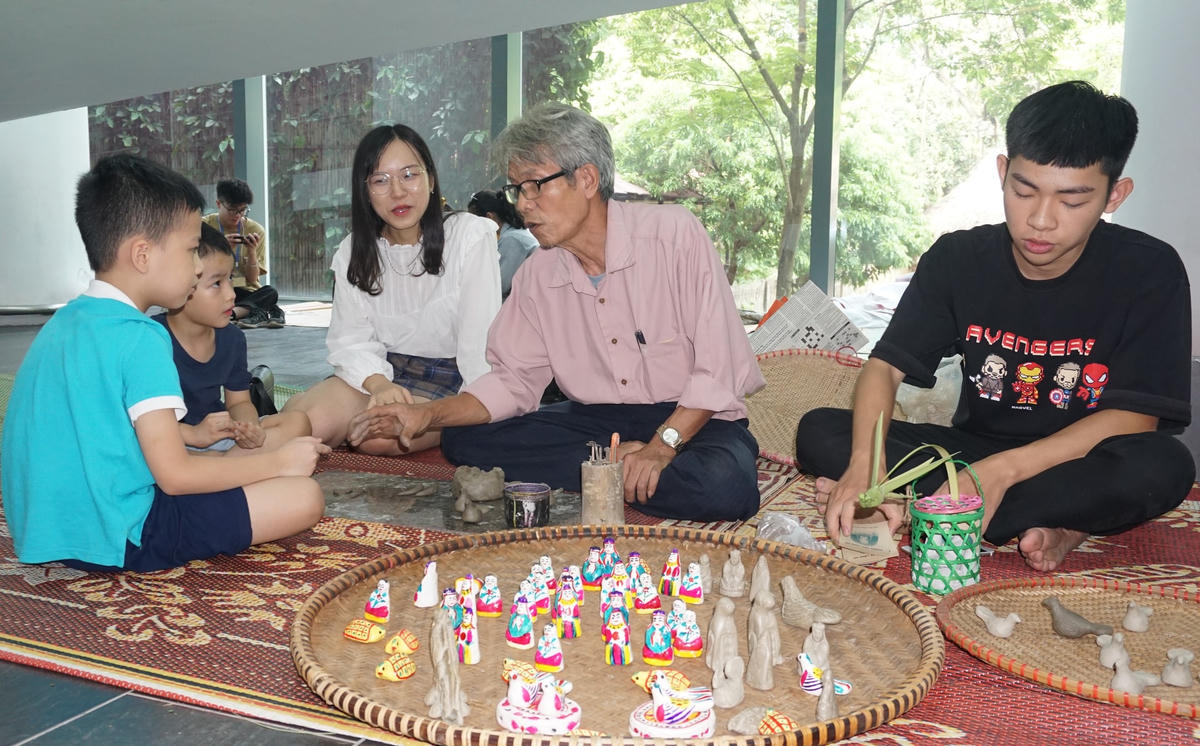 Nghệ nhân Phùng Đình Giáp giảng giải về phỗng đất cho các cháu thiếu niên.