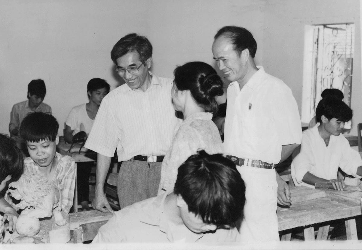 Hiệu trưởng Trịnh Quốc Đạt (người đứng sau) giới thiệu với lãnh đạo Bộ Lâm nghiệp lớp học nghề chạm khắc gỗ (năm 1993).  
