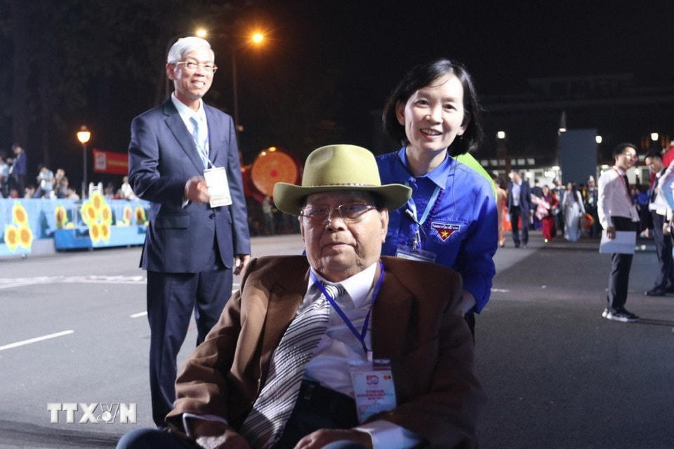 Một đại biểu cao tuổi được tình nguyện viên hỗ trợ vào vị trí. (Ảnh: TTXVN)