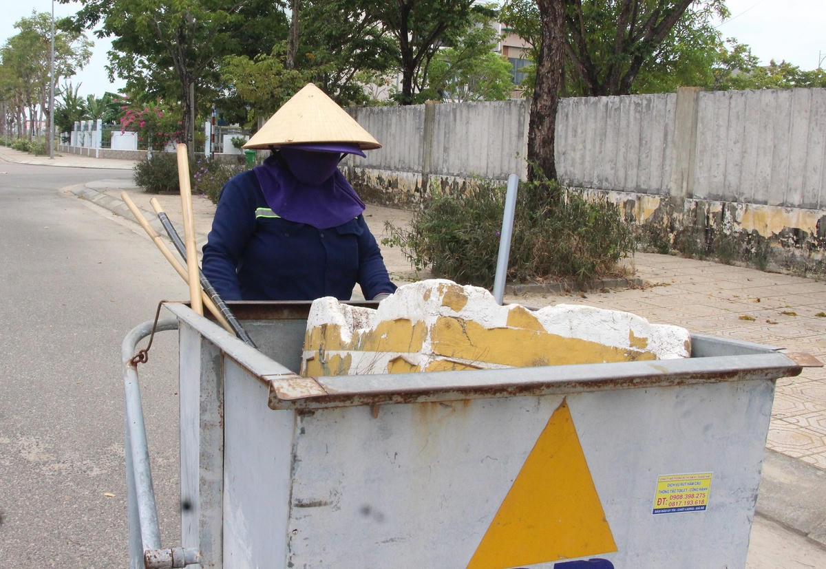 Đẩy xe rác đi thu gom rác thải.