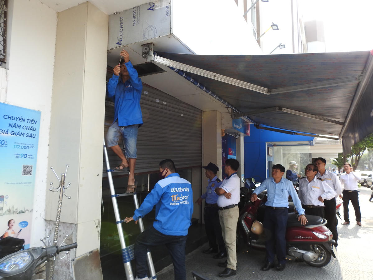 Nhóm thợ đang sửa lại cửa cuốn của chi nhánh ngân hàng tại số 3 - 5 đường Đống Đa sau vụ cướp. Ảnh: Thanh Tùng.