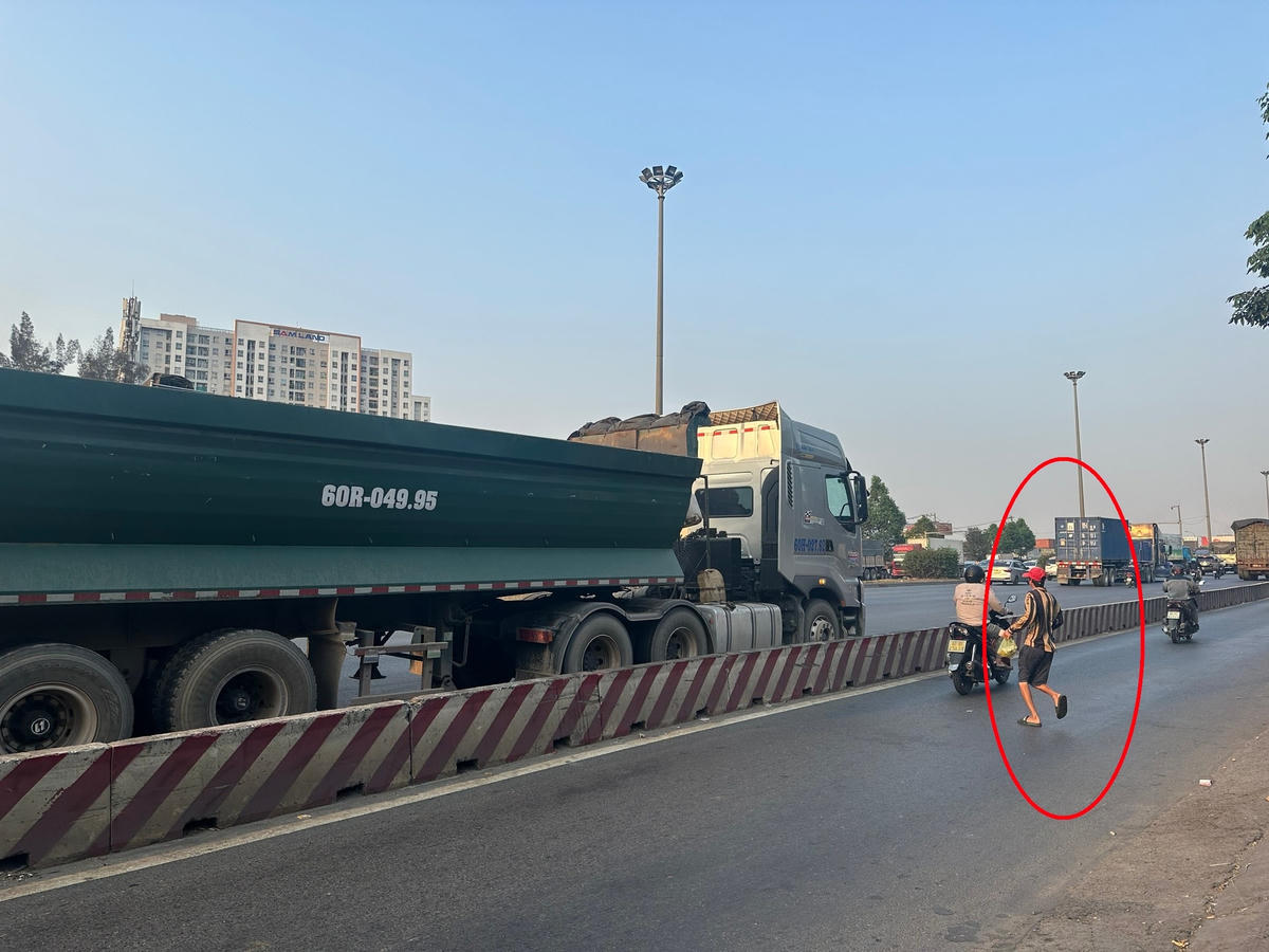 Người đàn ông lao nhanh giữa đại lộ giao cơm cho tài xế (khoanh đỏ). Ảnh: Mạnh Thìn.