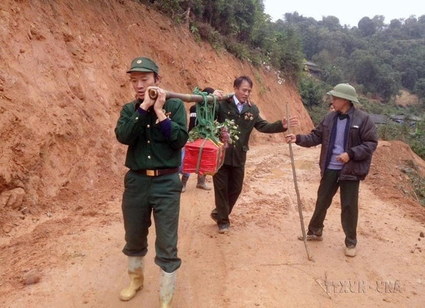 Cựu chiến binh Nguyễn Văn Kim và đồng đội đưa hài cốt liệt sĩ Đình Văn Chung (hy sinh trên cao điểm 900, mặt trận Vị Xuyên, Hà Giang) về nghĩa trang liệt sĩ xã Thanh Thủy. Ảnh: TTXVN.