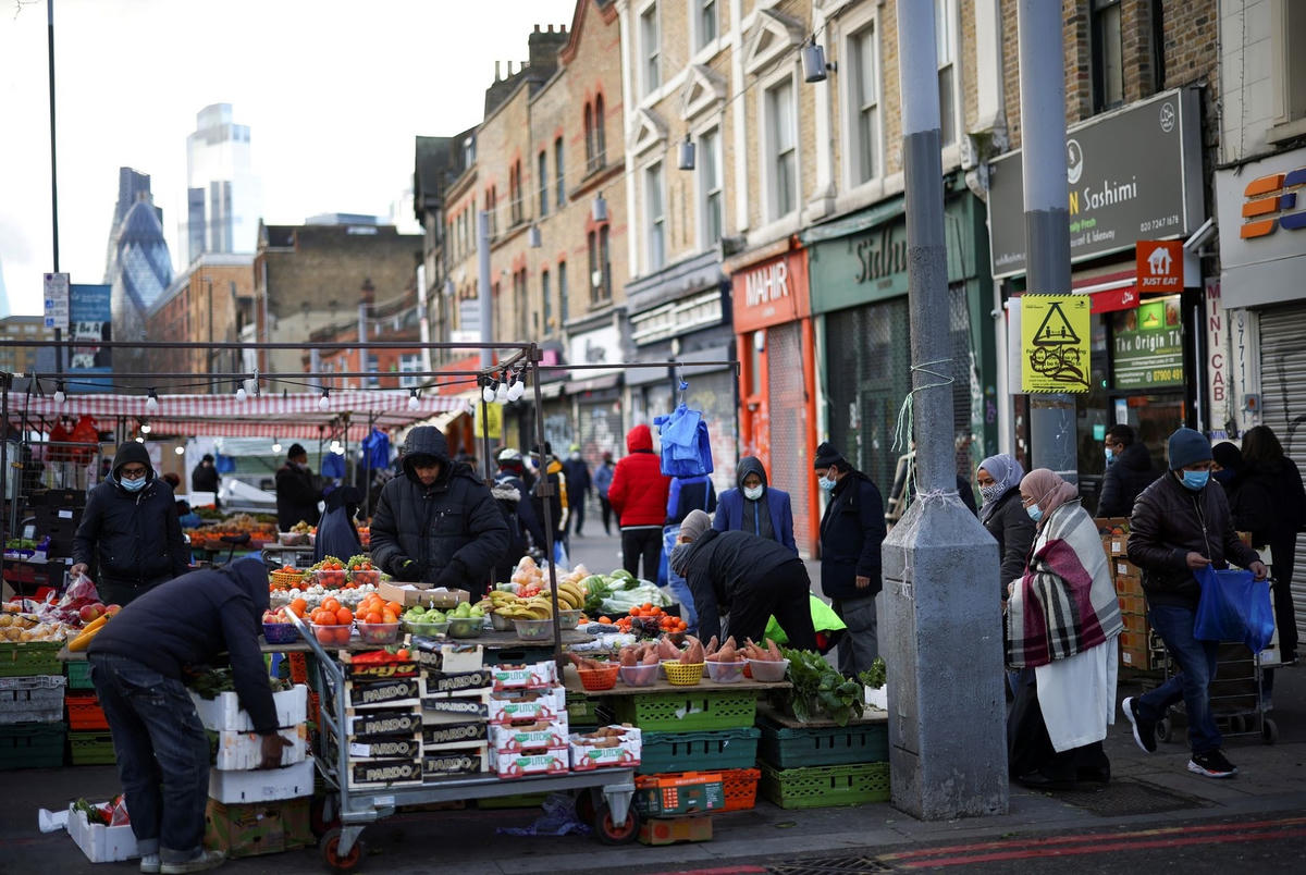Người dân mua sắm trong một khu chợ ở phía đông London (Anh). Ảnh: Reuters.