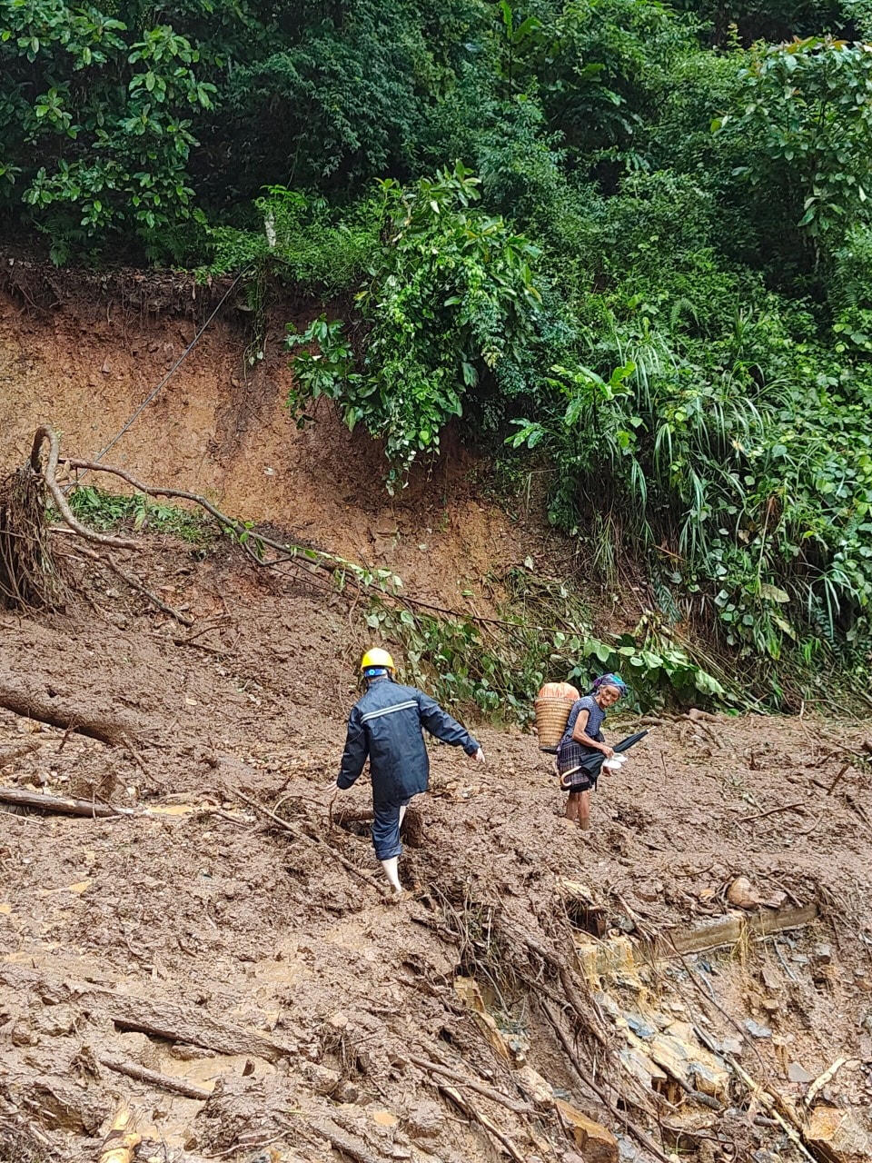 Công nhân Điện lực tại Sơn La hỗ trợ người dân qua khu vực sạt lở.