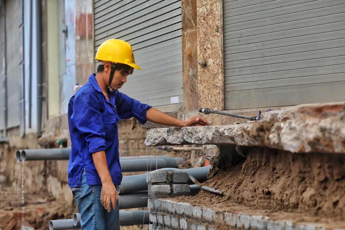 Công nhân xây tường chắn để ngăn cách công trình giao thông với nhà dân.