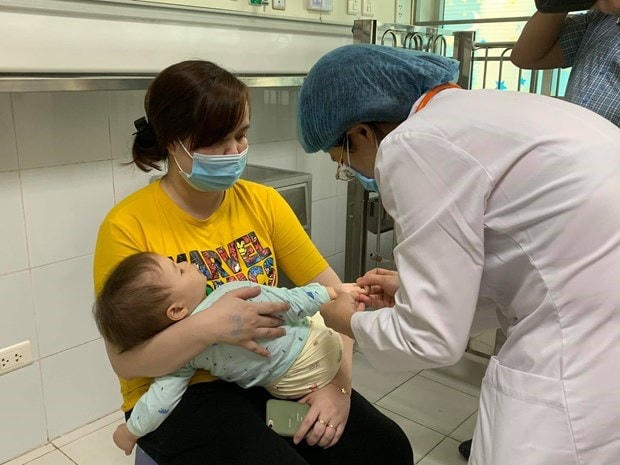 Bác sĩ kiểm tra sức khỏe cho trẻ mắc bệnh tay chân miệng tại Bệnh viện Nhi trung ương. Nguồn: TTXVN.