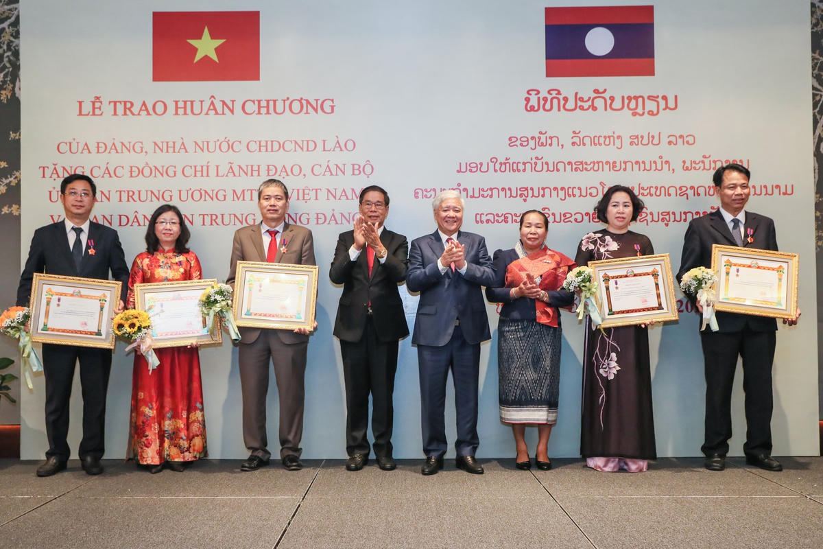 Chủ tịch Uỷ ban Trung ương Mặt trận Lào xây dựng đất nước Sinlavong Khoutphaythoune và Chủ tịch Uỷ ban Trung ương MTTQ Việt Nam Đỗ Văn Chiến chụp ảnh lưu niệm với các cá nhân được nhận Huân chương Lao động hạng III.