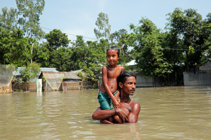 Một người đàn ông Bangladesh nâng con trai vượt qua vùng lũ. Ảnh: AFP.  