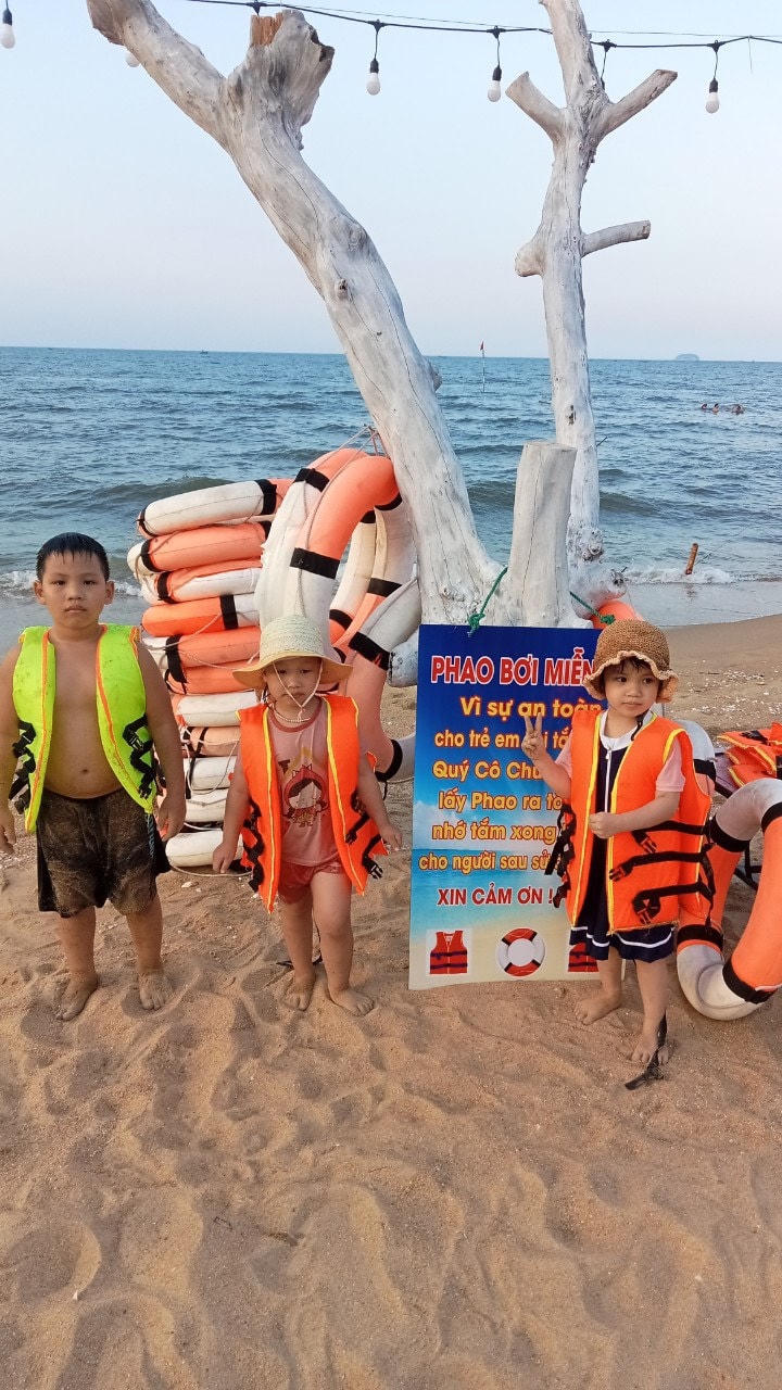 Hình ảnh những em nhỏ vui vẻ mặc áo phao miễn phí để tắm biển an toàn.