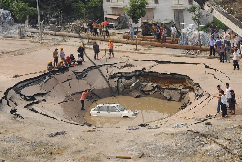 Một chiếc ô tô bị mắc kẹt đang được cẩu lên khỏi "hố tử thần" ở Quảng Châu, tỉnh Quảng Đông, Trung Quốc vào ngày 7/9/2008. Ảnh: Reuters.