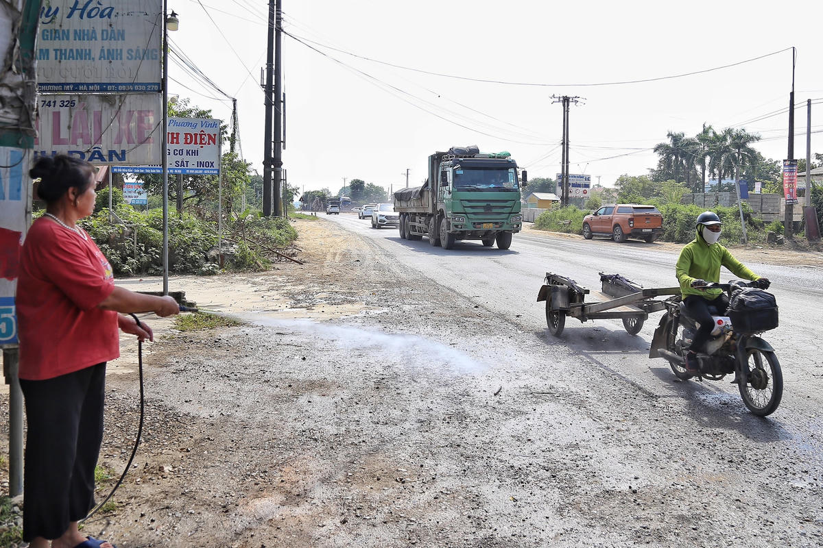 Người dân phải tưới nước ra đường để tránh bụi bặm.