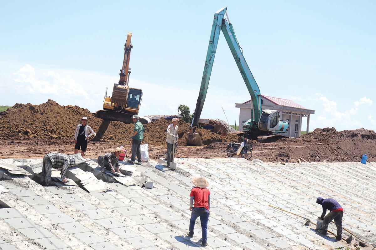 Các khối bê tông đúc sẵn được công nhân lắp ghép để tạo thành mặt đê.  
