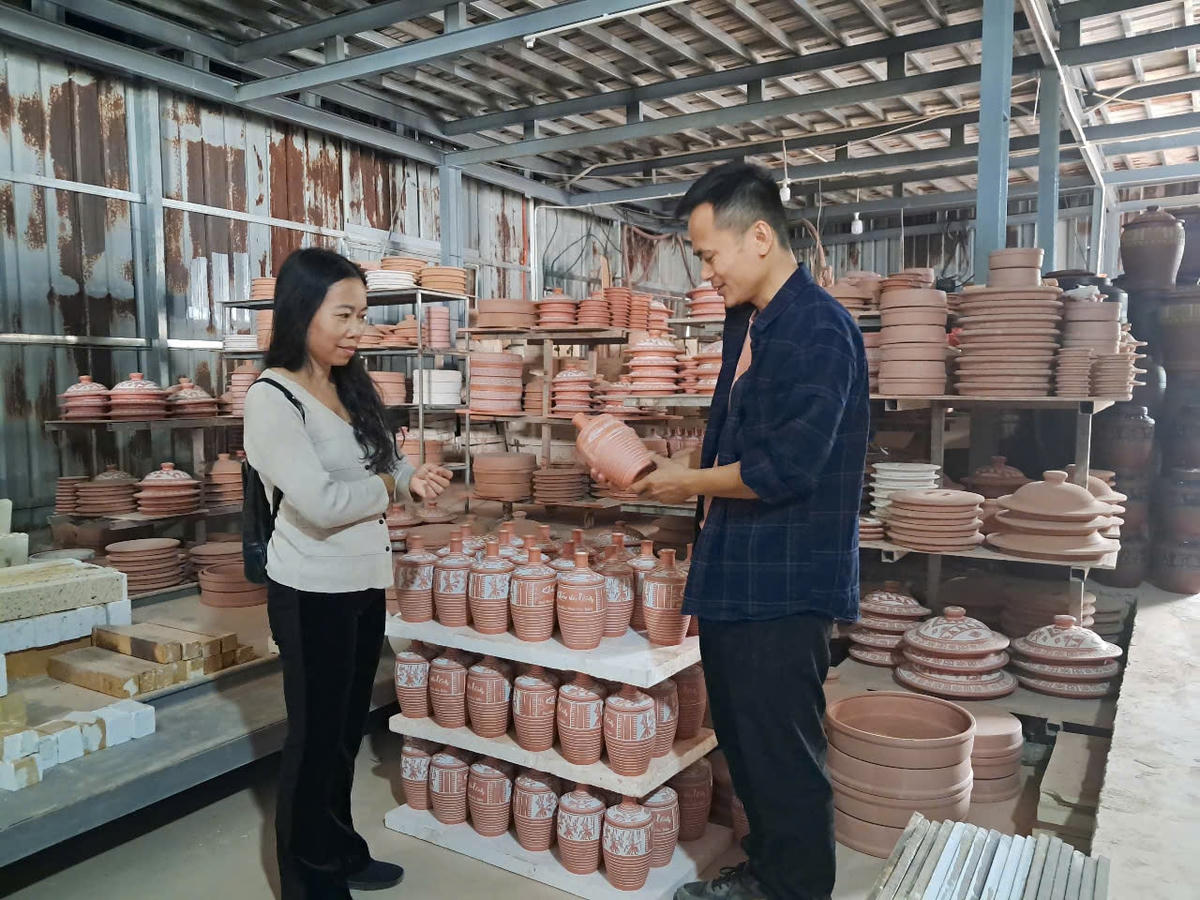 Nghệ nhân Nguyễn Mạnh Hòa (áo đen) chia sẻ kỹ thuật làm gốm tại xưởng gốm của gia đình. 