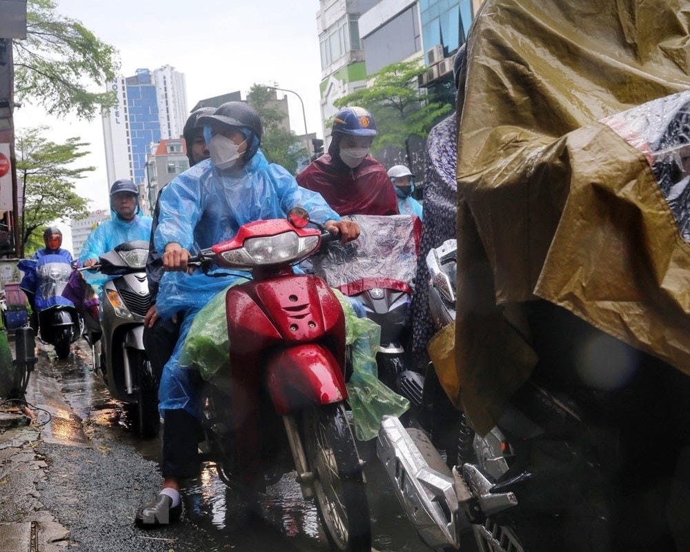 Cơn mưa to khiến người dân di chuyển khó khăn trên phố Tây Sơn sáng 6/6. Ảnh: TTXVN.