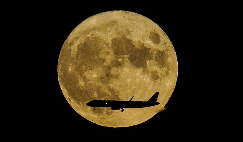 Siêu trăng mọc lên khi một máy bay phản lực tiếp cận sân bay Quốc tế John F Kennedy, New York. Ảnh: AP.