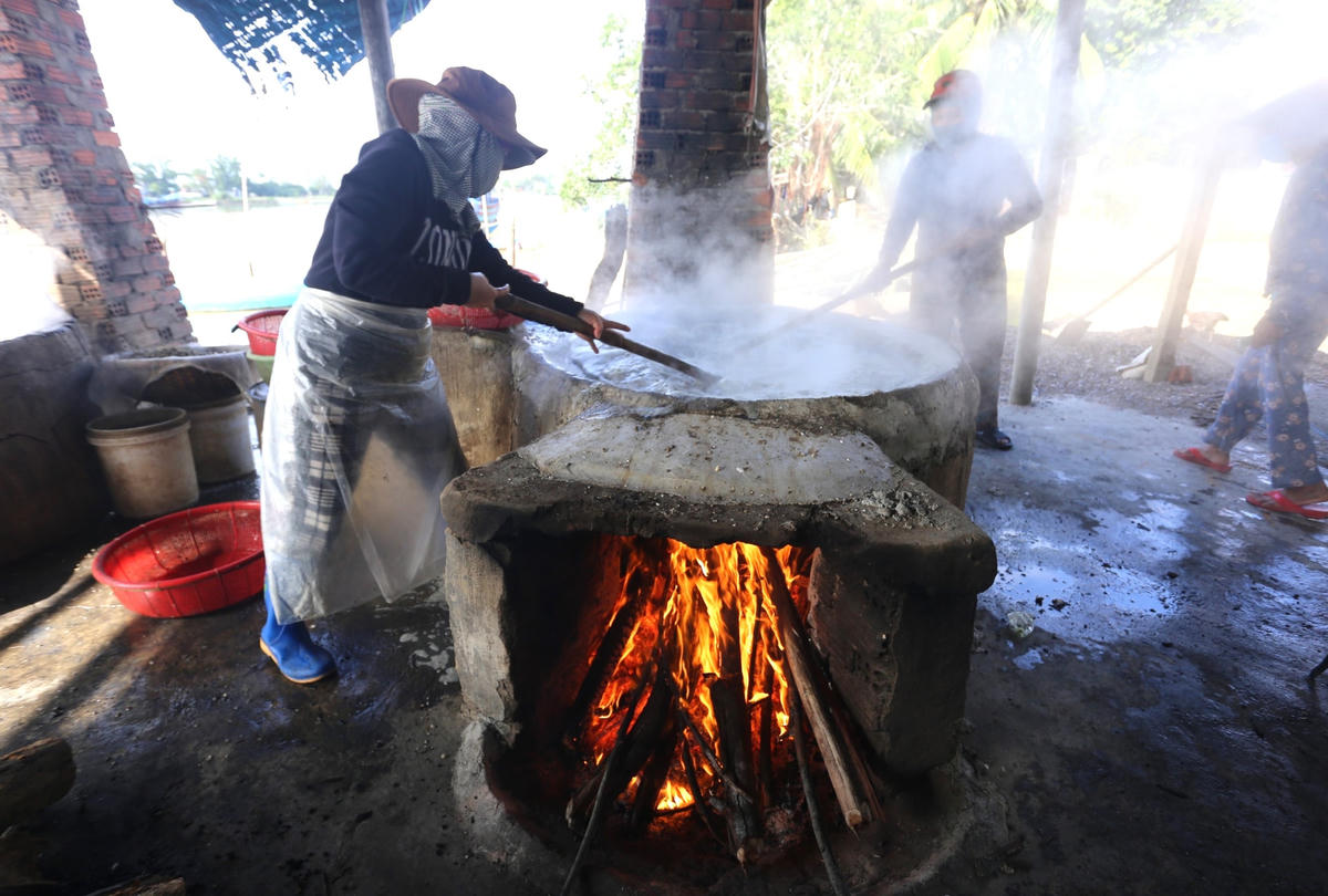 Người dân đang nấu hến trên bếp lửa đỏ.
