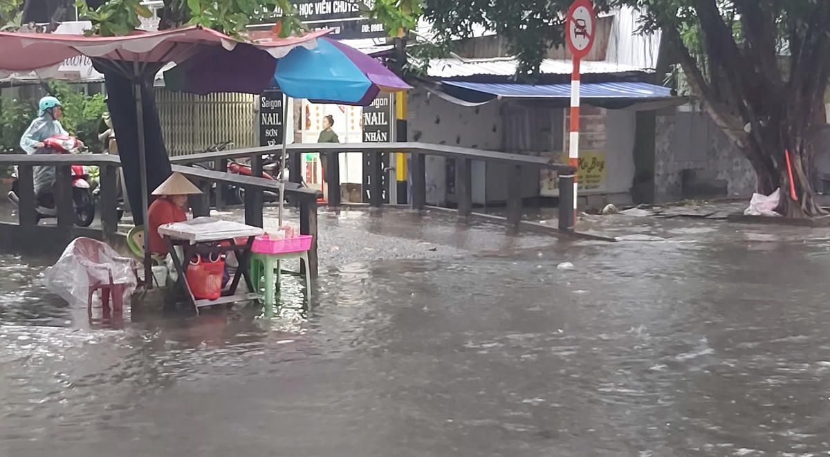 Người bán vé số gần cầu Chùa “chịu trận” vì đường bị ngập.