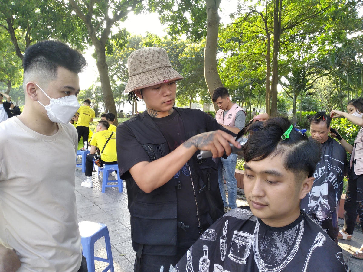 Anh Thành, chủ tiệm cắt tóc Thành Mán Barber gần hồ Đền Lừ đang hướng dẫn một bạn cắt tóc miễn phí tại hồ. Ảnh: Lê Trang.