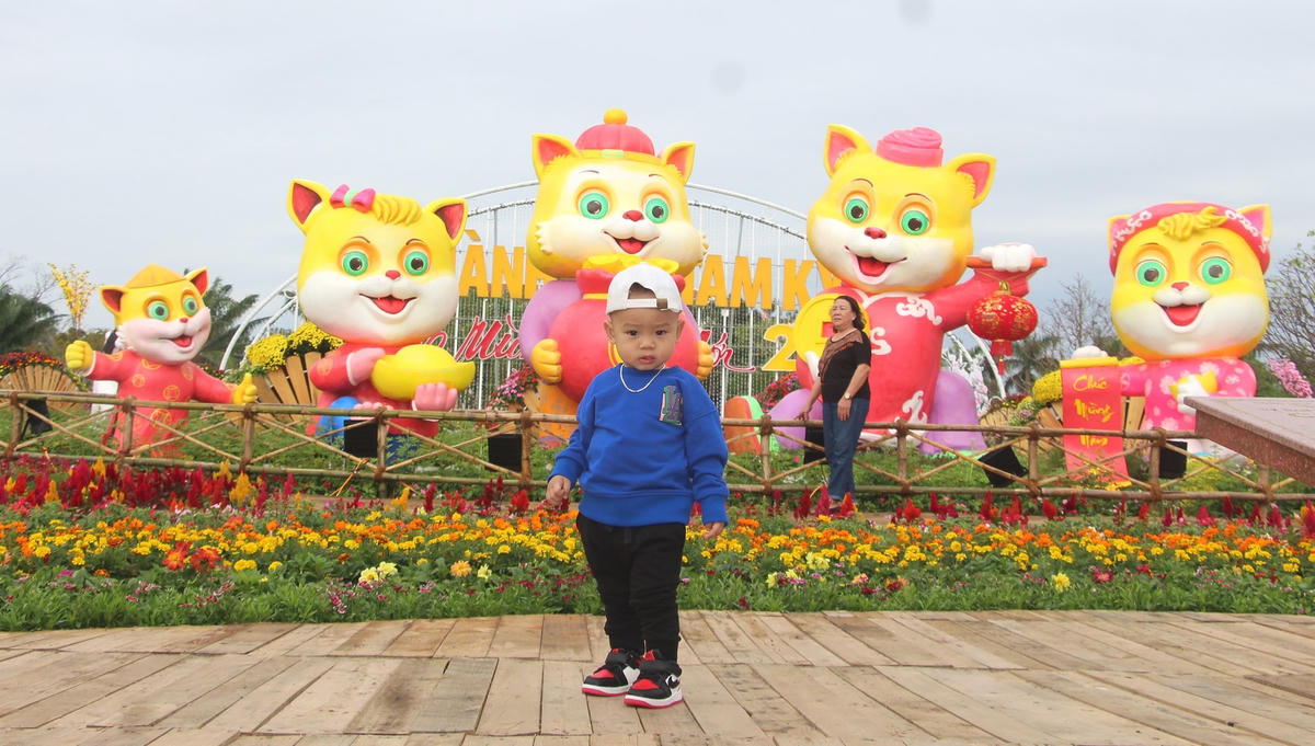 Em nhỏ được phụ huynh chụp ảnh bên linh vật mèo. 