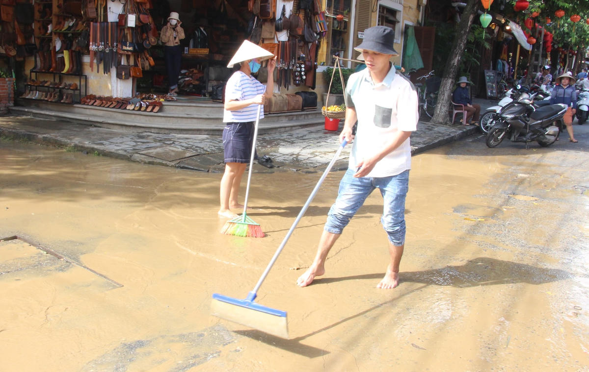 Anh Trần Công Chinh đang dọn bùn non trên mặt đường.