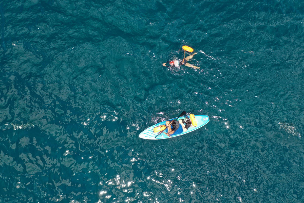 Lực lượng cứu hộ chèo thuyền theo VĐV bơi để đảm bảo an toàn.