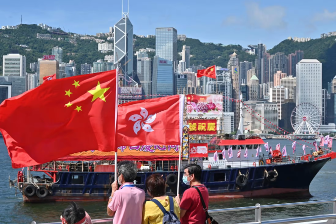 Người dân Hong Kong vẫy cờ Trung Quốc và cờ đặc khu hôm 28/6, trong một sự kiện kỷ niệm 25 năm thành phố trở về với Trung Quốc đại lục. Ảnh: The Guardian.