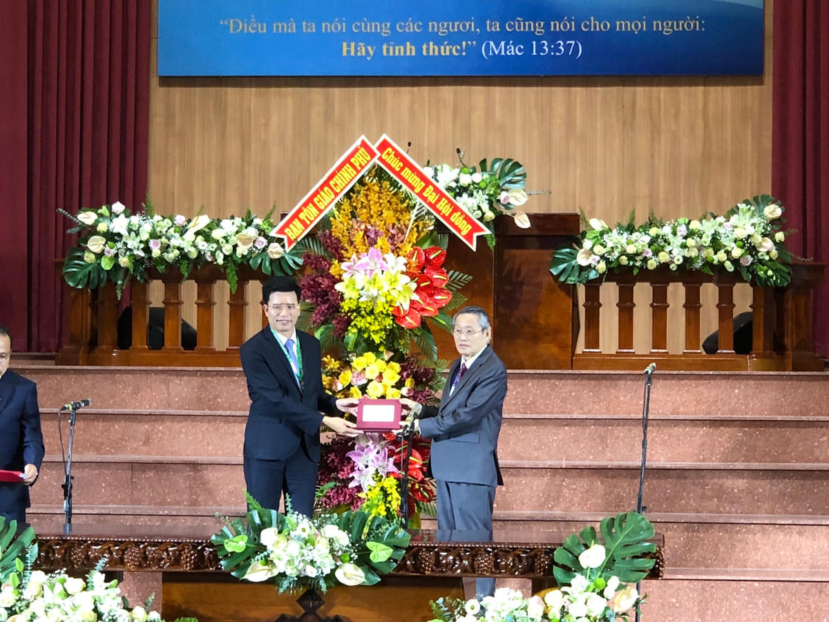 Mục sư Thái Phước Trường, Hội trưởng Hội thánh Tin lành Việt Nam (miền Nam) nhận lẵng hoa chúc mừng từ ông Nguyễn Tiến Trọng, Phó trưởng Ban Tôn giáo Chính phủ (bên trái). (Ảnh: Hồng Phúc).