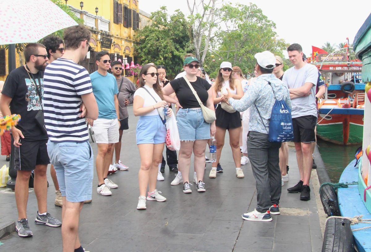 Du khách nước ngoài nghe giới thiệu về phố cổ Hội An.