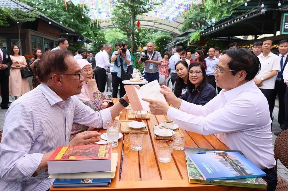 Thủ tướng Phạm Minh Chính tặng sách cho Thủ tướng Malaysia Anwar Ibrahim và Phu nhân. (Ảnh: Dương Giang/TTXVN).