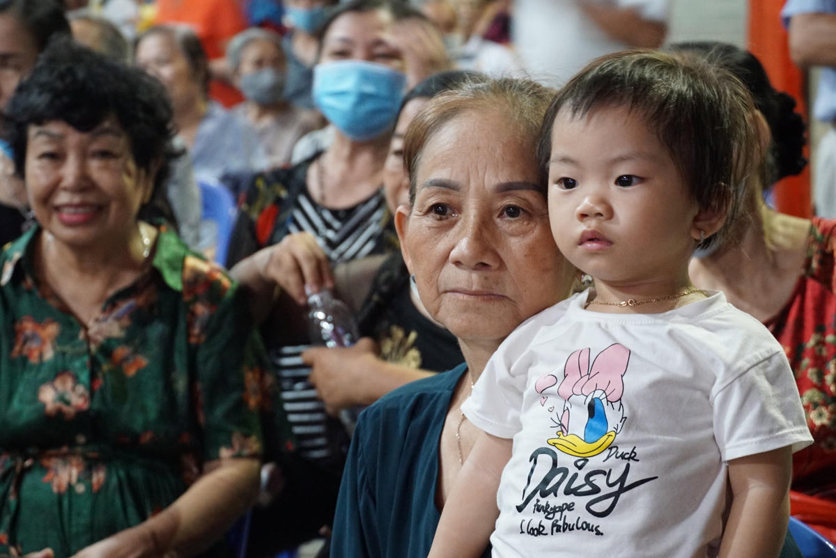 Một em bé đi theo người thân chăm chú theo dõi chương trình. Ảnh: Mạnh Thìn.