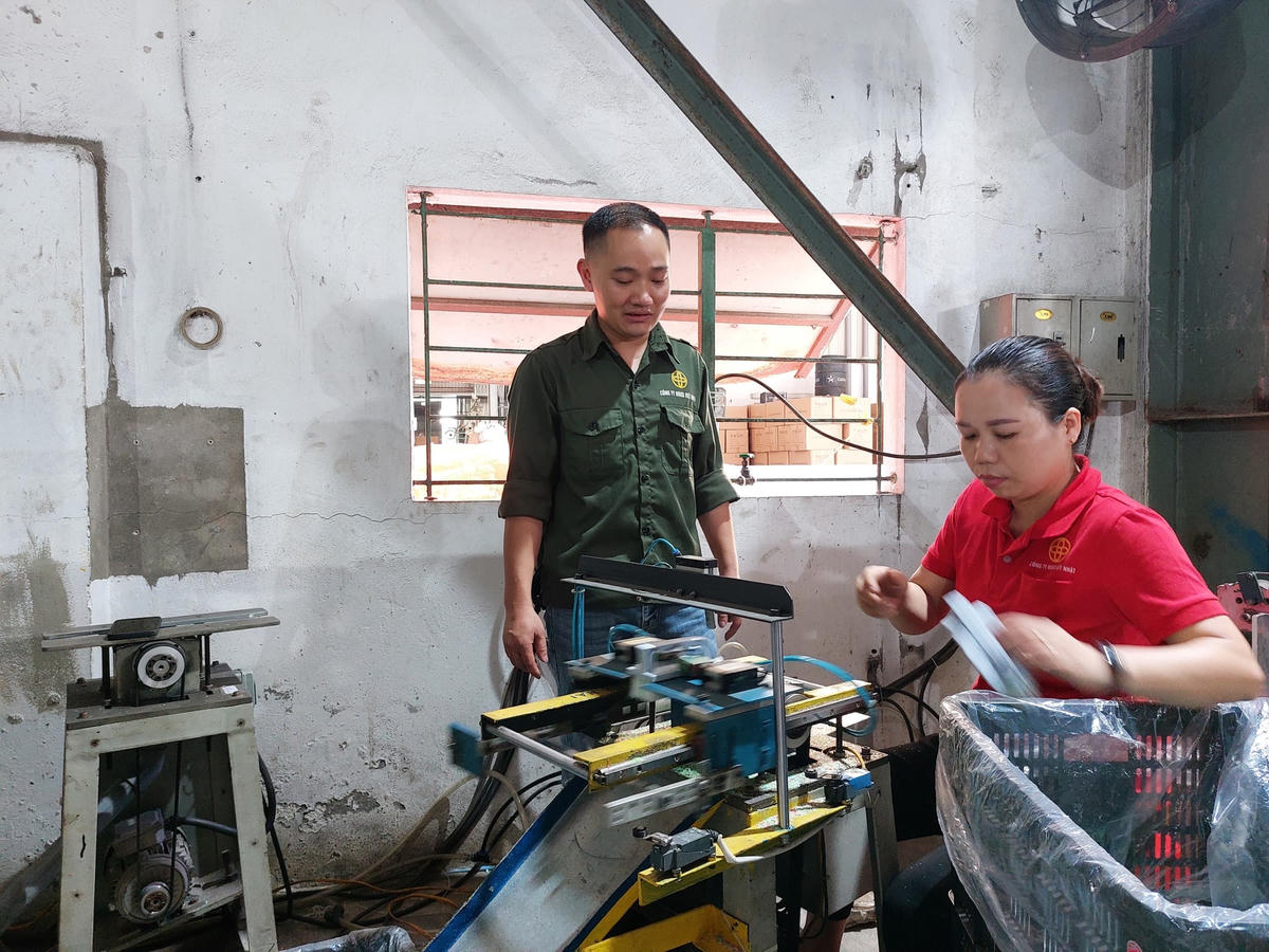 Anh Trần Quốc Hai hướng dẫn đồng nghiệp cắt cước bàn chải bằng máy.