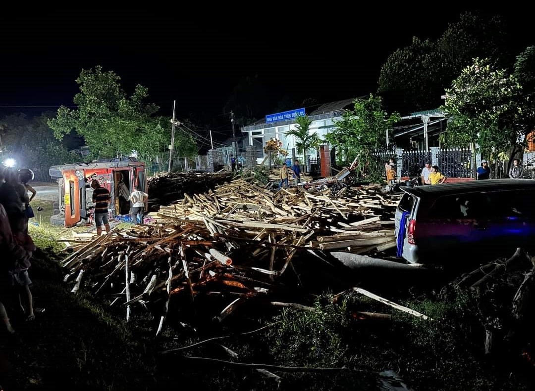 Nhiều gỗ keo trên xe tải lật tràn ra đường.