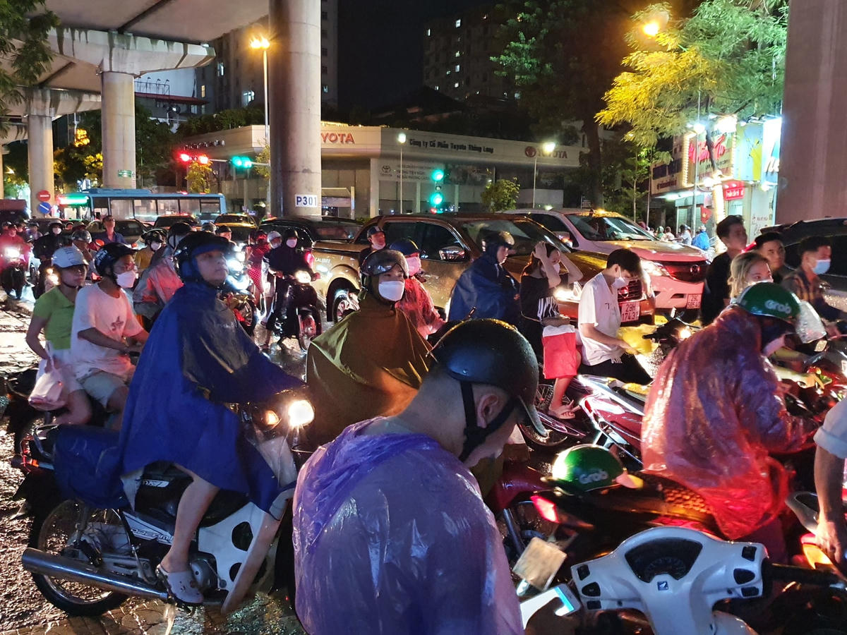 Hàng trăm người dân tập trung trên vỉa hè đợi nước cạn để di chuyển, trong khi lượng phương tiện đổ về ngày càng nhiều khiến con đường này trở nên ùn tắc nghiêm trọng.