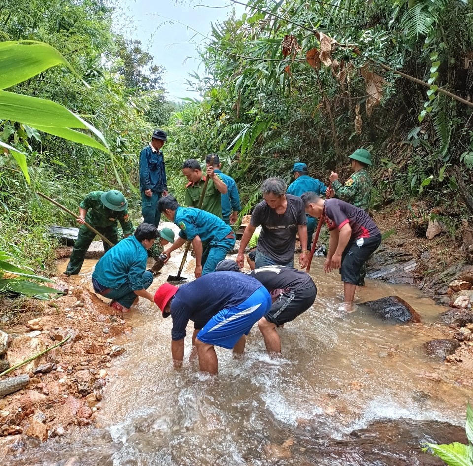 Lực lượng chức năng cùng người dân khắc phục đường liên xã bị sạt lở.