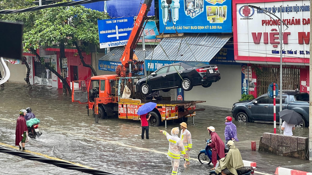 Cảnh xe ô tô bị ngập nước, chết máy, phải cứu hộ.  Lực lượng cứu hộ ở địa phương phải hoạt động rất vất vả.