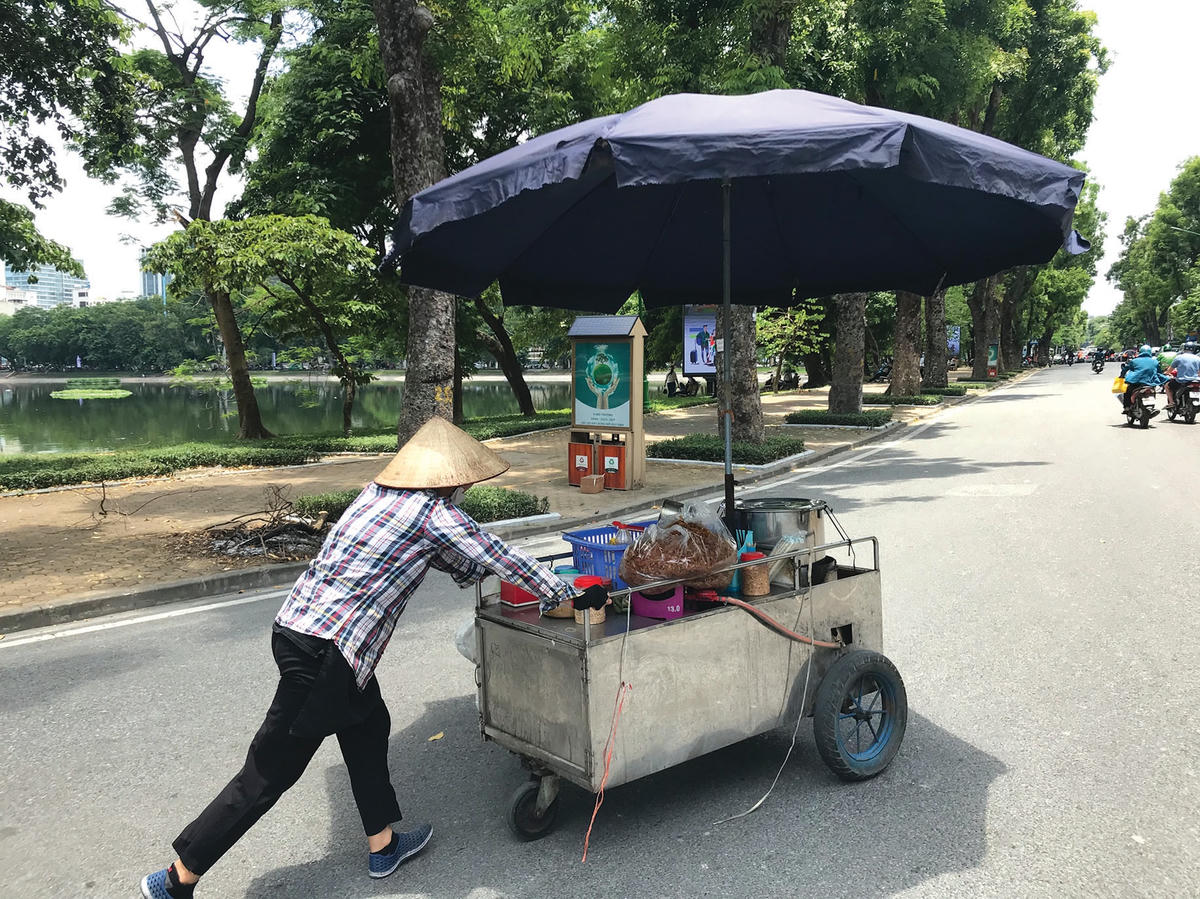 Giữa trưa nắng, người phụ nữ bán bánh đa đẩy vội xe hàng đến địa điểm mới trên phố Quang Trung để phục vụ thực khách.  